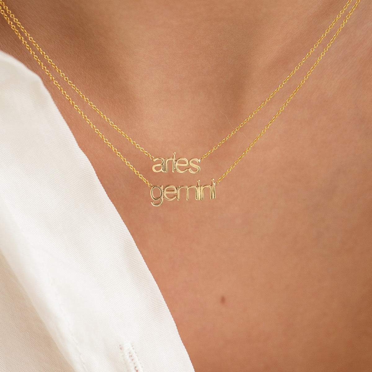 a woman wearing 2 zodiac yellow gold nameplate necklaces