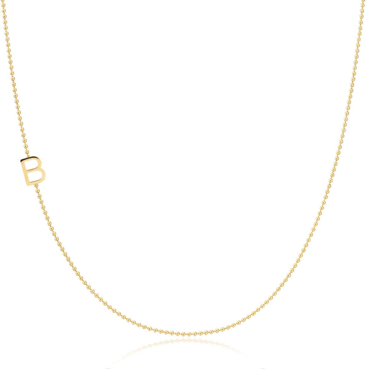 Gold beaded necklace with a 'B' charm on a white background.