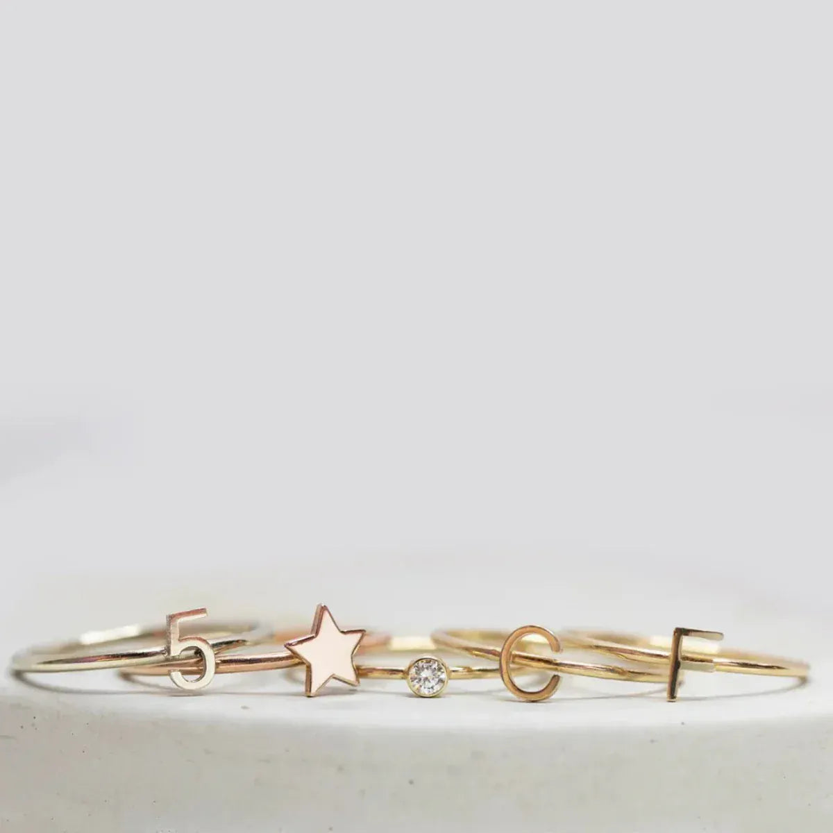 Five gold rings, including two Letter Rings (C and F), a Number 5 Ring, a Twinkle Twinkle Ring and a Birthstone Ring.
