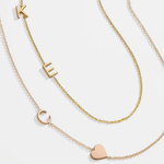 A yellow gold Custom Gold Necklace with two letters (K and E) and a Monogram Necklace with Heart Rose Gold with a letter C charm, against a white background.
