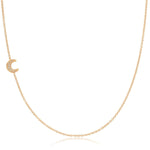 Gold cable necklace with a pave crescent moon charm on a white background. 