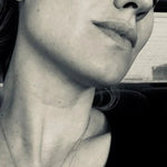 A black and white close-up photo of woman wearing a Sharktooth Necklace with Diamond Ridge with a black top. 