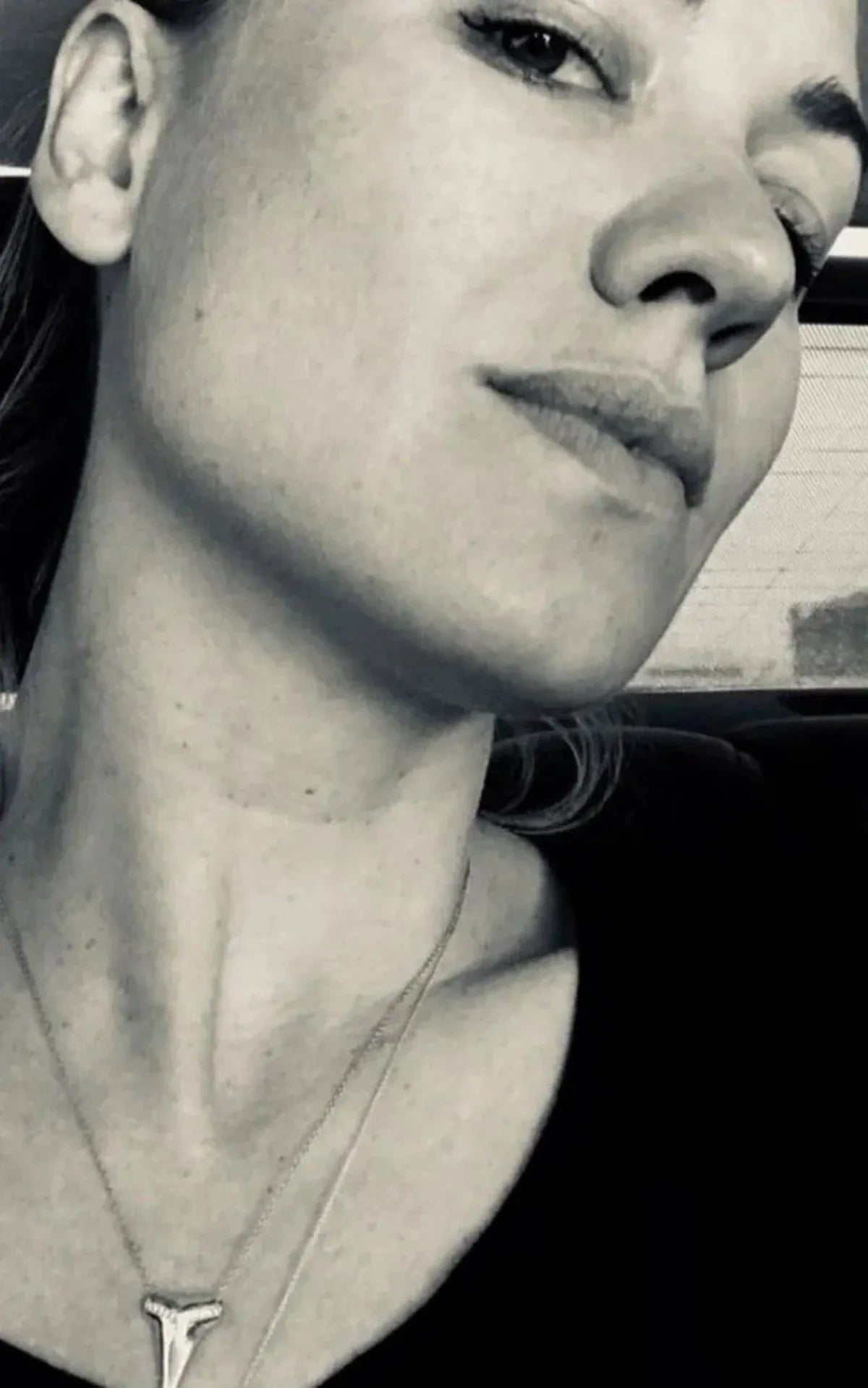 A black and white close-up photo of woman wearing a Sharktooth Necklace with Diamond Ridge with a black top. 