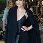 A brunette woman wearing a Sharktooth Necklace with Pavé Top layered with another long necklace, dressed in black clothing inside a jewellery store.