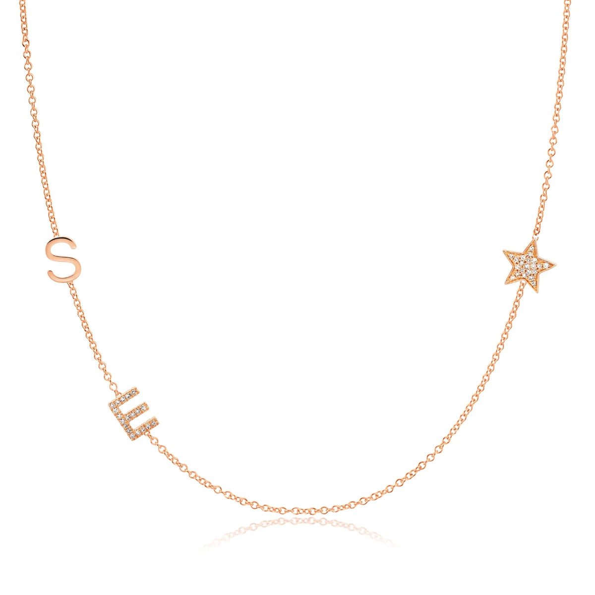 A Custom Gold Necklace in rose gold with two letter charms, a pavé E and an S positioned on the left side of the necklace, and a star charm positioned on the right side, on a white background.