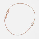 A rose gold bracelet with an B letter charm on a white background. 