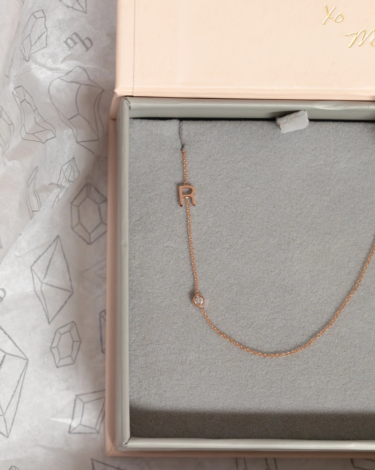 A Monogram Necklace with Diamond Rose Gold and a letter R charm in a Maya Brenner jewellery box. 