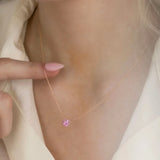 Close-up of a neck wearing The Sweetheart Necklace - Pink Sapphire in rose gold with a cream shirt.