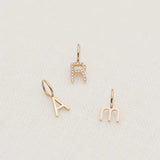 A Petite Letter Charm in m, a Gold Letter Charm in A and a Pavé Letter Charm in R, all in rose gold, against a white textured background. 