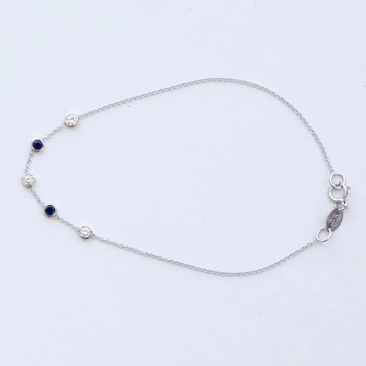 A white gold Custom Gold Bracelet – 5 Letters with five birthstones (three diamond and two sapphire) on a white background.