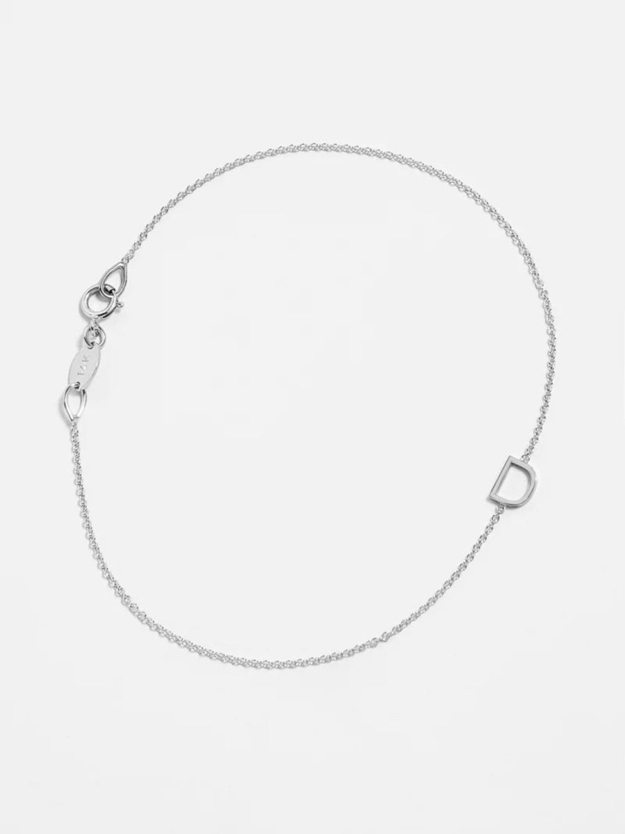 A white gold bracelet with an D letter charm on a white background. 