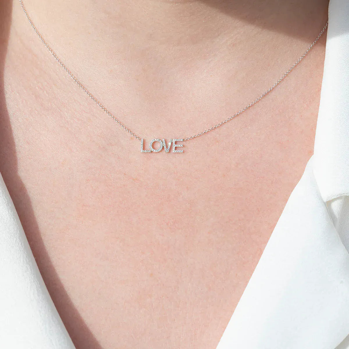 A Pavé LOVE Necklace in white gold on a cable chain on a white background. 