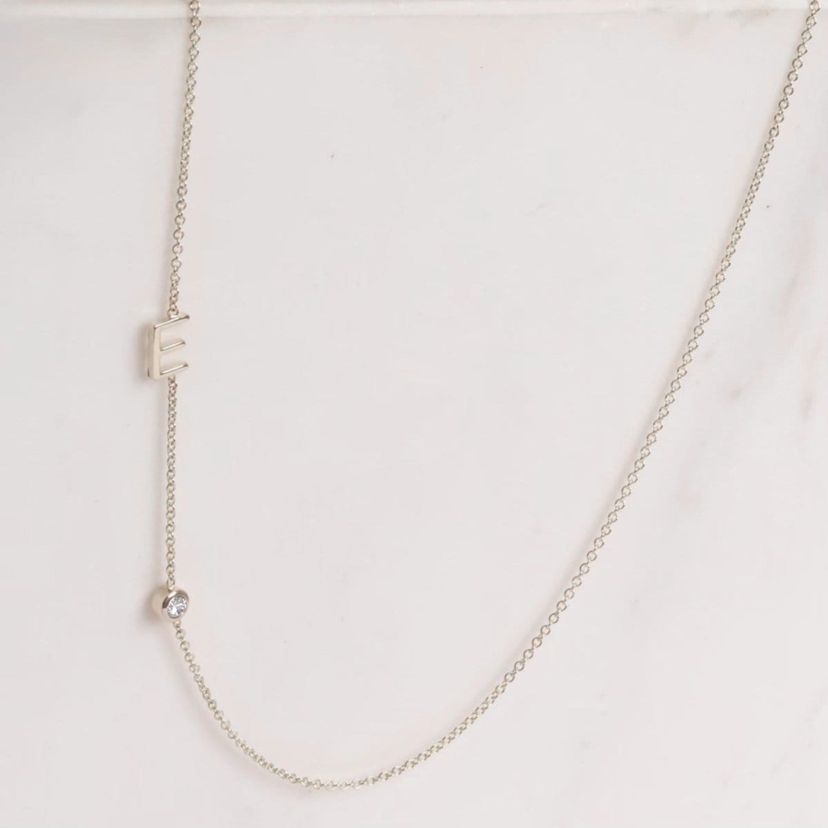 A Monogram Necklace with Diamond White Gold and a letter E charm on a light grey background. 