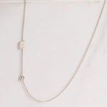 A Monogram Necklace with Diamond White Gold and a letter E charm on a light grey background. 