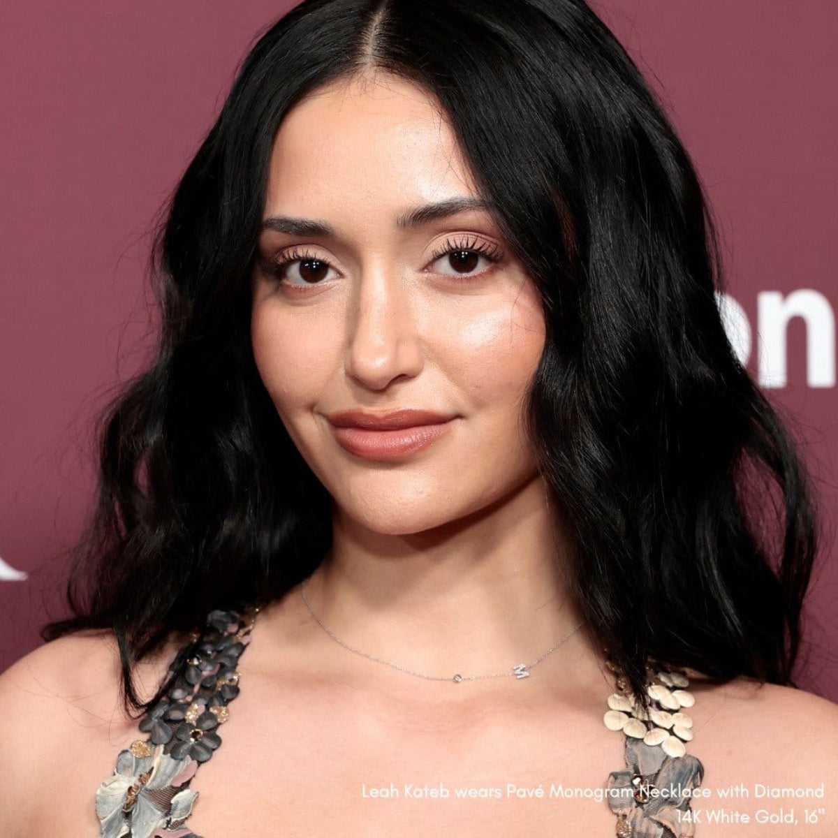 Internet personality, Leah Kateb wearing a Pavé Monogram Necklace with Diamond and a letter M charm in white gold, against a maroon background.