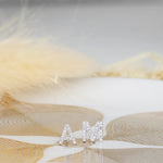 White gold pave letter stud earrings A and M on a white and gold surface. 