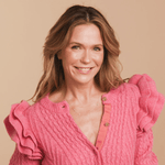 American actress Katie Aselton Duplass in a bright pink top wearing a Custom Gold Necklace with three birthstone charms, two on the left and one on the right of the necklace, against a neutral background.