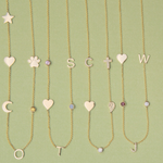Four Custom Gold Necklaces in yellow gold, three with five different charms and one with six, laid against a light green background.