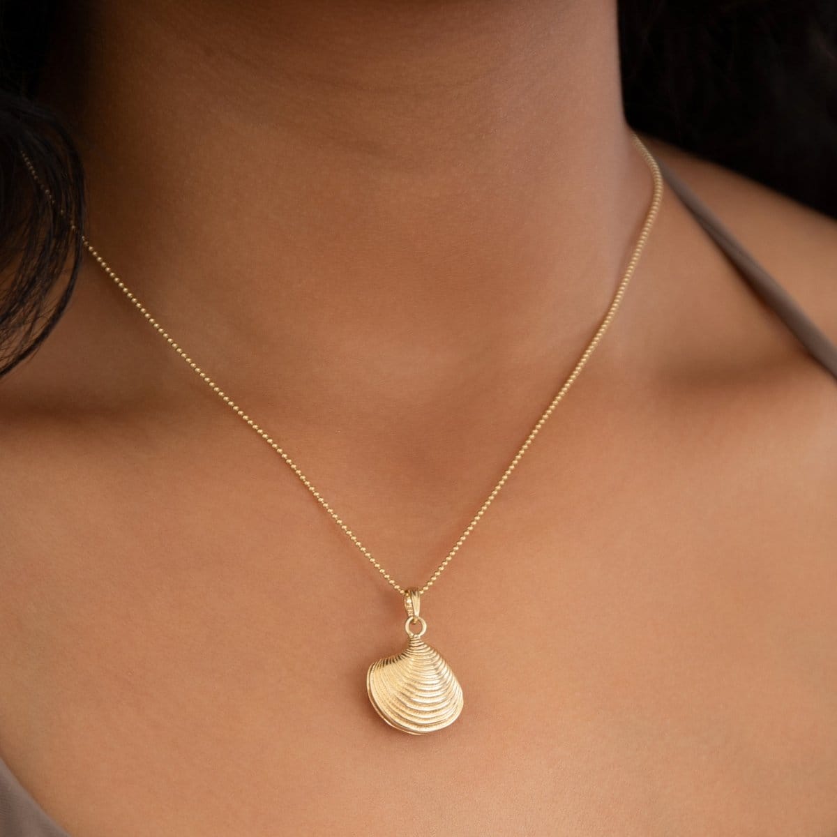 Close-up of a neck wearing a Classic Bead Chain with a Golden Coast Shell. 