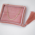  The Everyday Diamond Necklace in a pink holder against a light grey background. 
