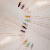 Several Retreat Necklaces in various colours on a cream soft-textured background.