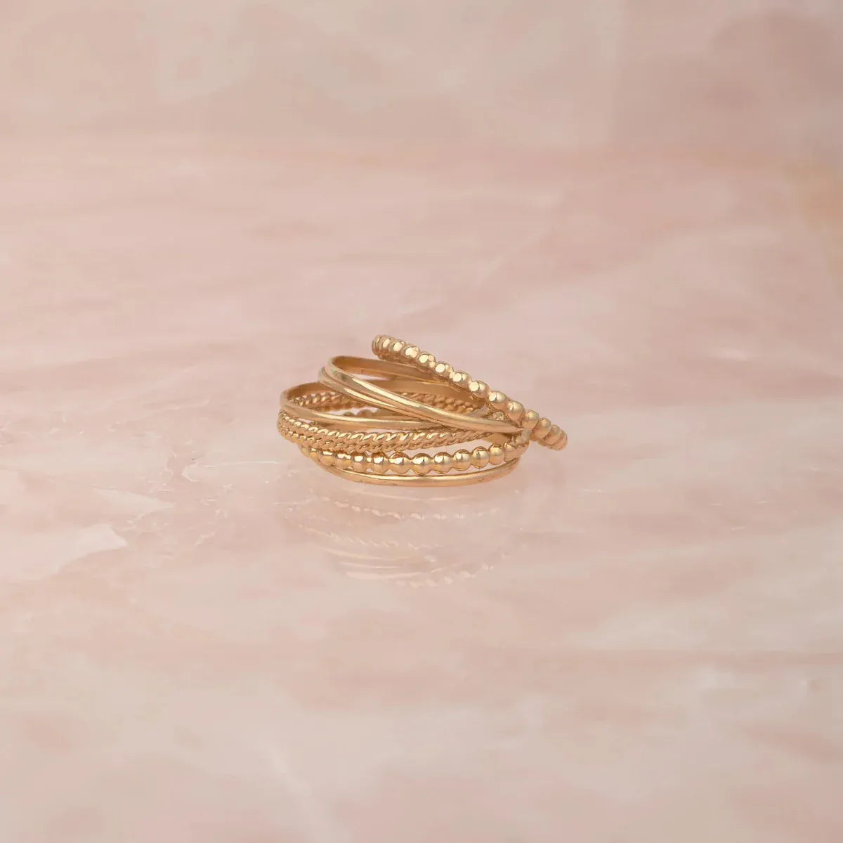 Delicate Trio Stacking Rings on a light pink marble background. 
