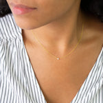 A close-up of a woman's neck wearing a yellow gold Diamond Layering Necklace, styled in a black and white stripe top. 