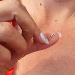 Close-up of a hand with a gold necklace featuring a letter E charm. 