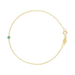 A yellow gold Birthstone Bracelet with a cable chain and an emerald birthstone on a white background. 