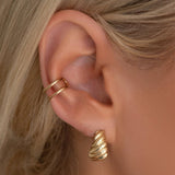Close-up of an Etched Paris Earring and Double Ear Cuff on a blonde woman's ear. 
