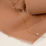 A Monogram Necklace with Heart and the letter T in yellow gold against a caramel brown piece of fabric. 