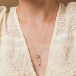 A close-up of a décolletage wearing The Clarity Necklace, styled with a cream top. 