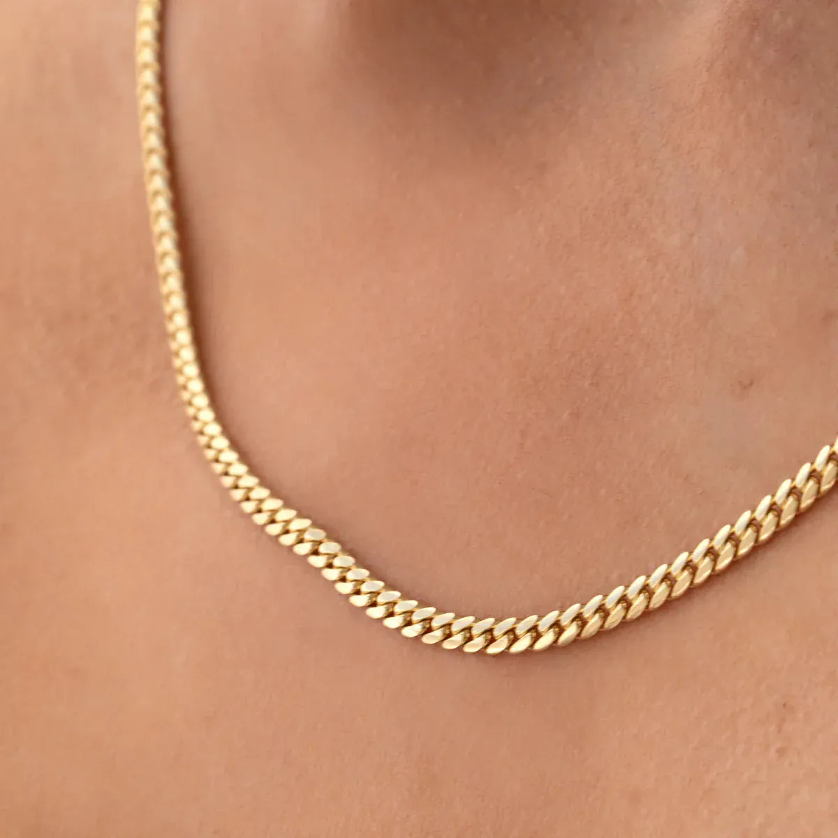 Close-up of a décolletage wearing a Chic Cuban Curb Chain in yellow gold. 
