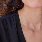 A close-up of a person's neck wearing a yellow gold 14k Gold Asymmetrical Charm Necklace - Pavé Star of David with a cable chain, styled with a navy top. 