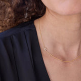 A close-up of a person's neck wearing a yellow gold 14k Gold Asymmetrical Charm Necklace - Pavé Star of David with a cable chain, styled with a navy top. 