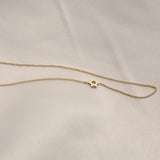 A yellow gold cable chain 14k Gold Asymmetrical Charm Necklace - Star of David against a light grey fabric background.