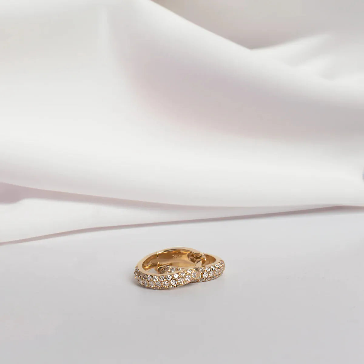 A pair of Pavé Huggies on a white background. 