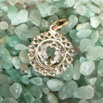 The Zodiac Necklace - Pisces pendant laid on top of small green crystal stones. 