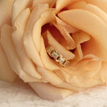 A yellow gold C'est Moi Link Ring nestled in a peach coloured rose.