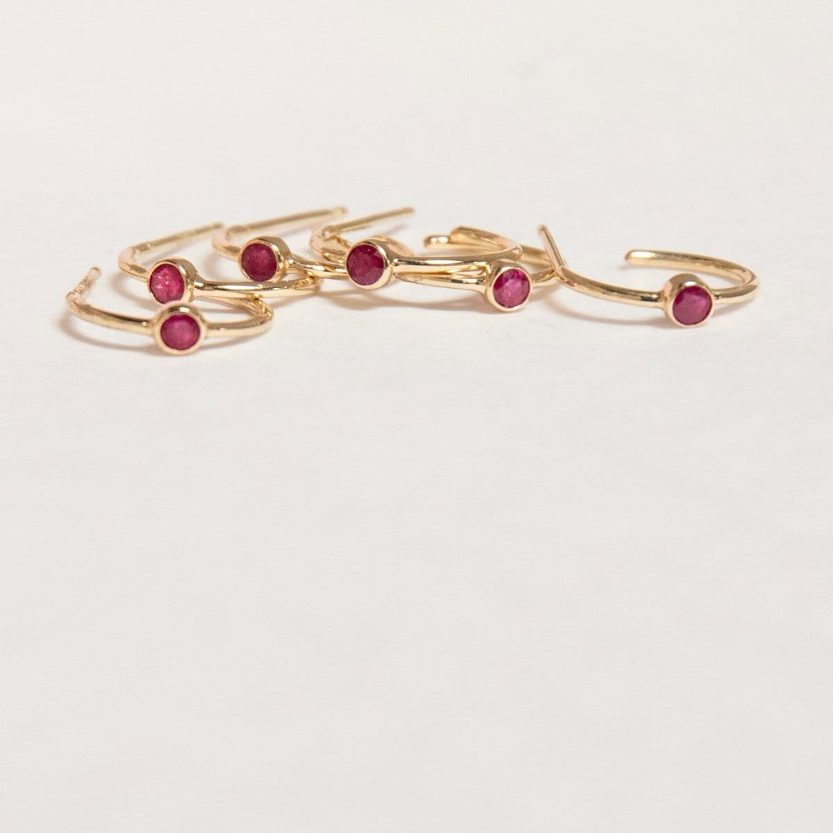 Several yellow gold Birthstone Hoops in Ruby - July on a white background. 