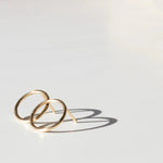A pair of Open Eclipse Earrings - Small in yellow gold against a light grey background. 