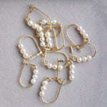 Several Tres Pearl Earrings against a light grey background. 