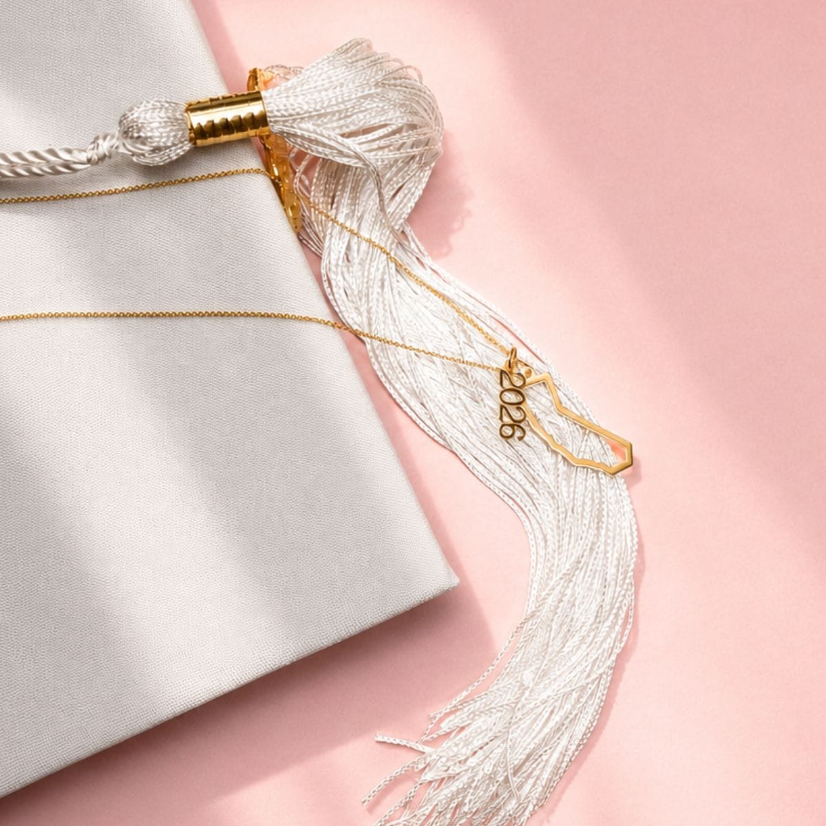 Close-up of a decorative tassel with gold accents on a light pink background