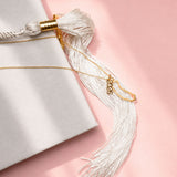 Close-up of a decorative tassel with gold accents on a light pink background