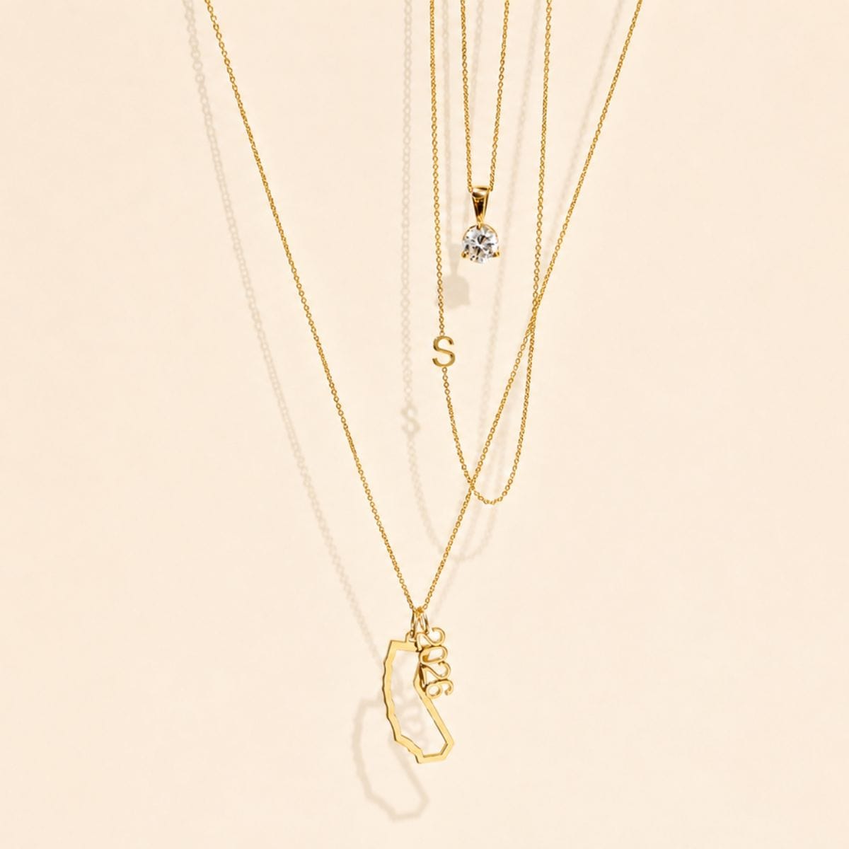 Gold necklaces with various pendants on a beige background