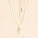 Gold necklaces with various pendants on a beige background