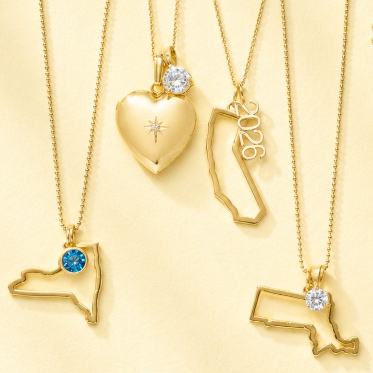 Gold necklaces with heart, state, and number 2026 pendants on a yellow background