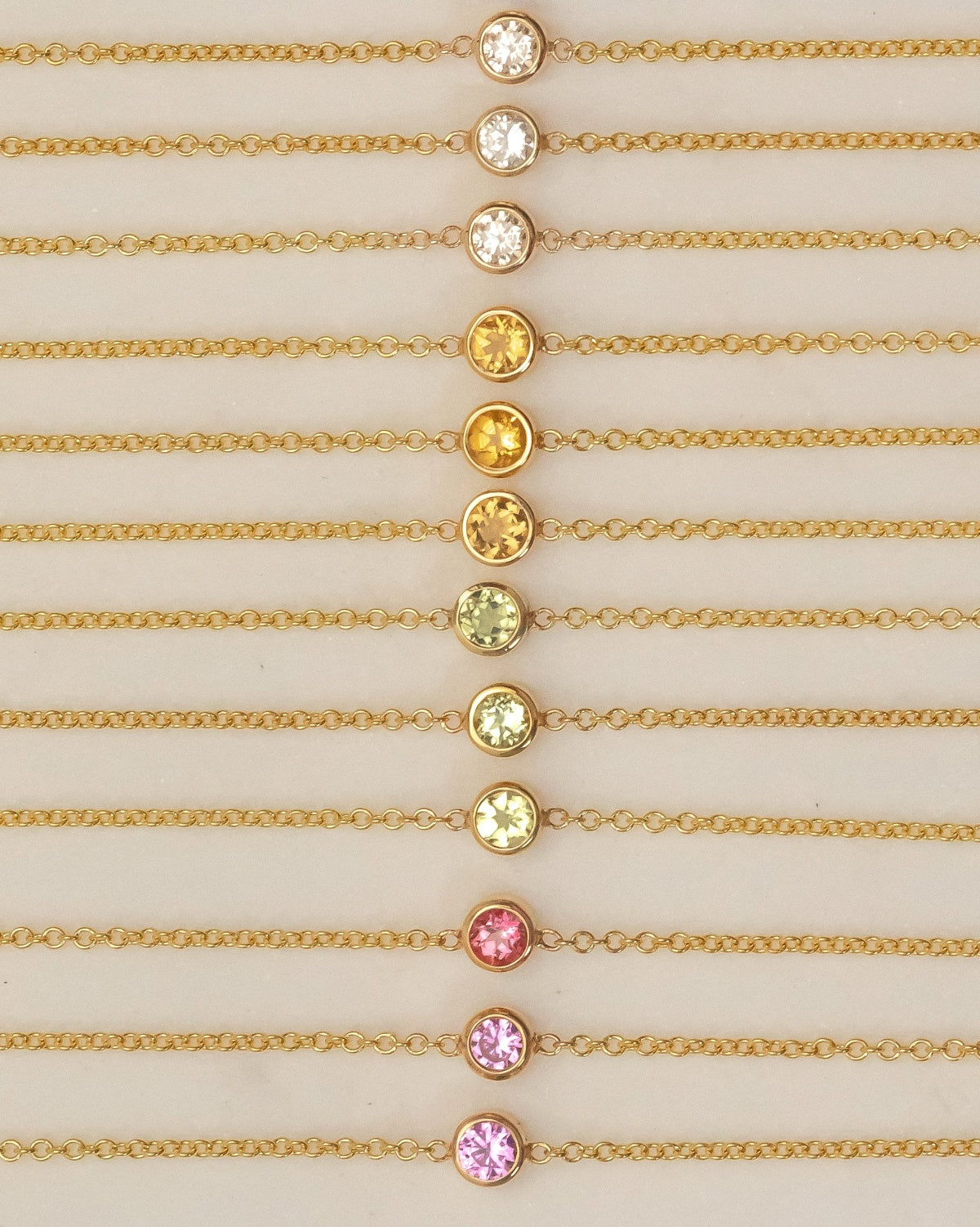 Gold necklaces with colorful gemstones on a beige background
