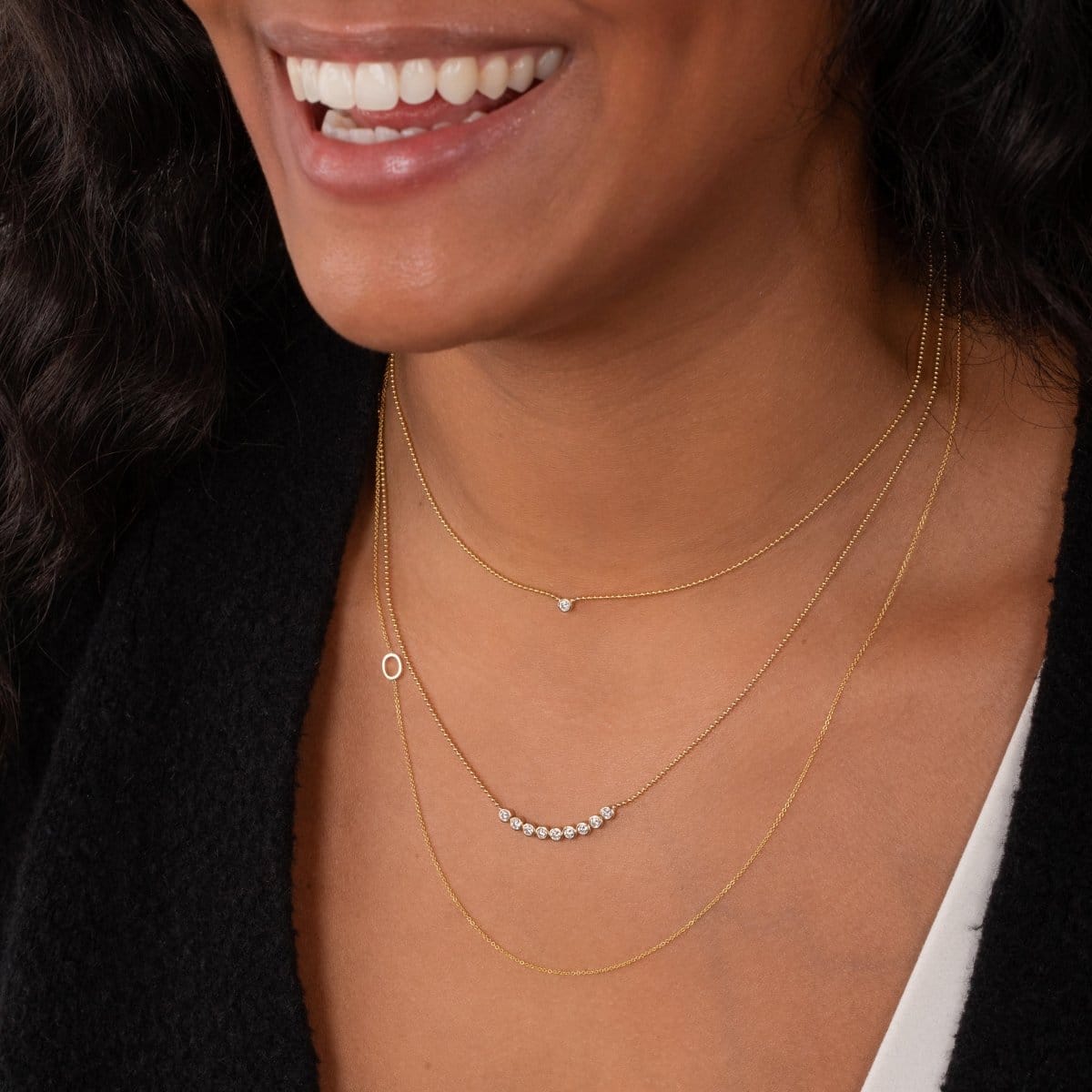 Close-up of a woman wearing multiple gold necklaces.