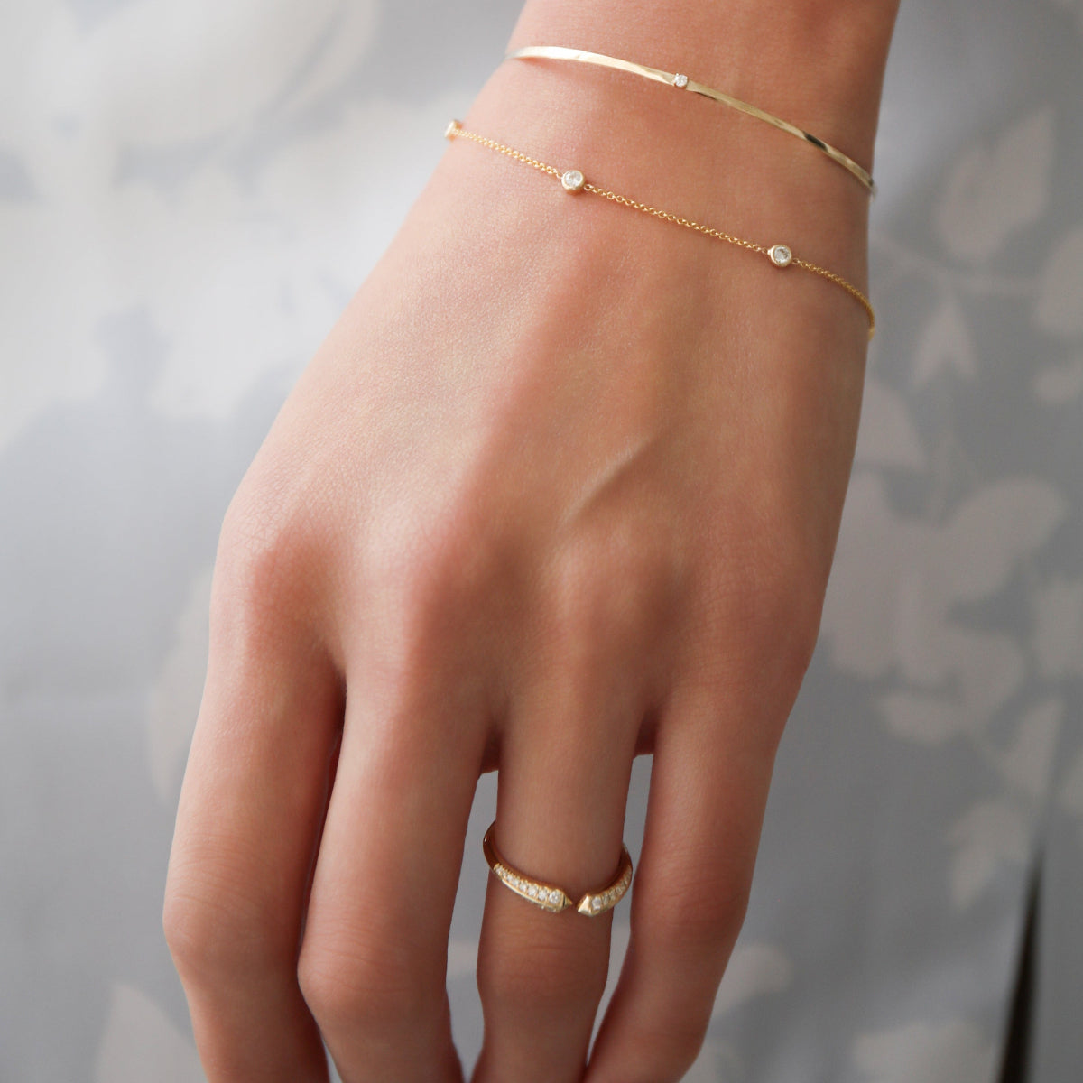 a close up of a woman wearing two diamond bracelets against a blue dress